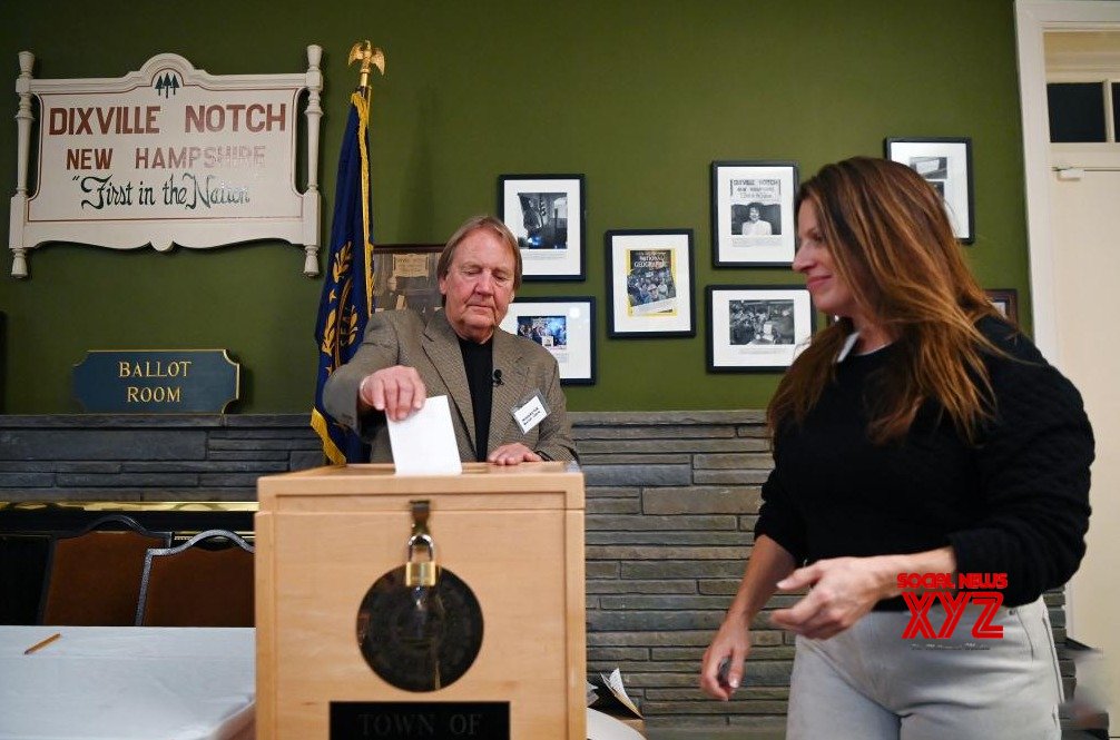 A moderator helps a voter (R) cast her ballot for the U.S. presidential election in Dixville Notch #Gallery